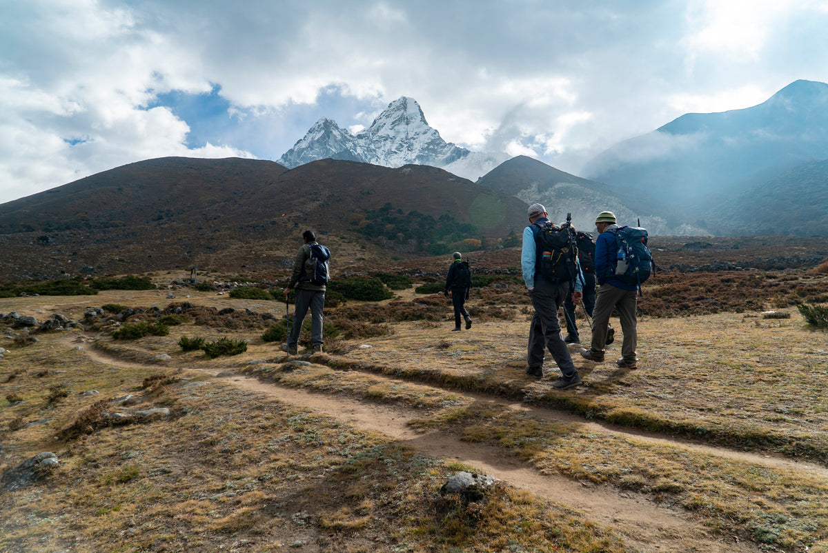 Trekkers crossing golden autumn grassland in the Everest region under a snow peak