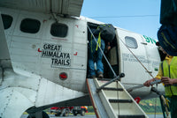 People boarding a small airplane with 'Great Himalaya Trails' branding.