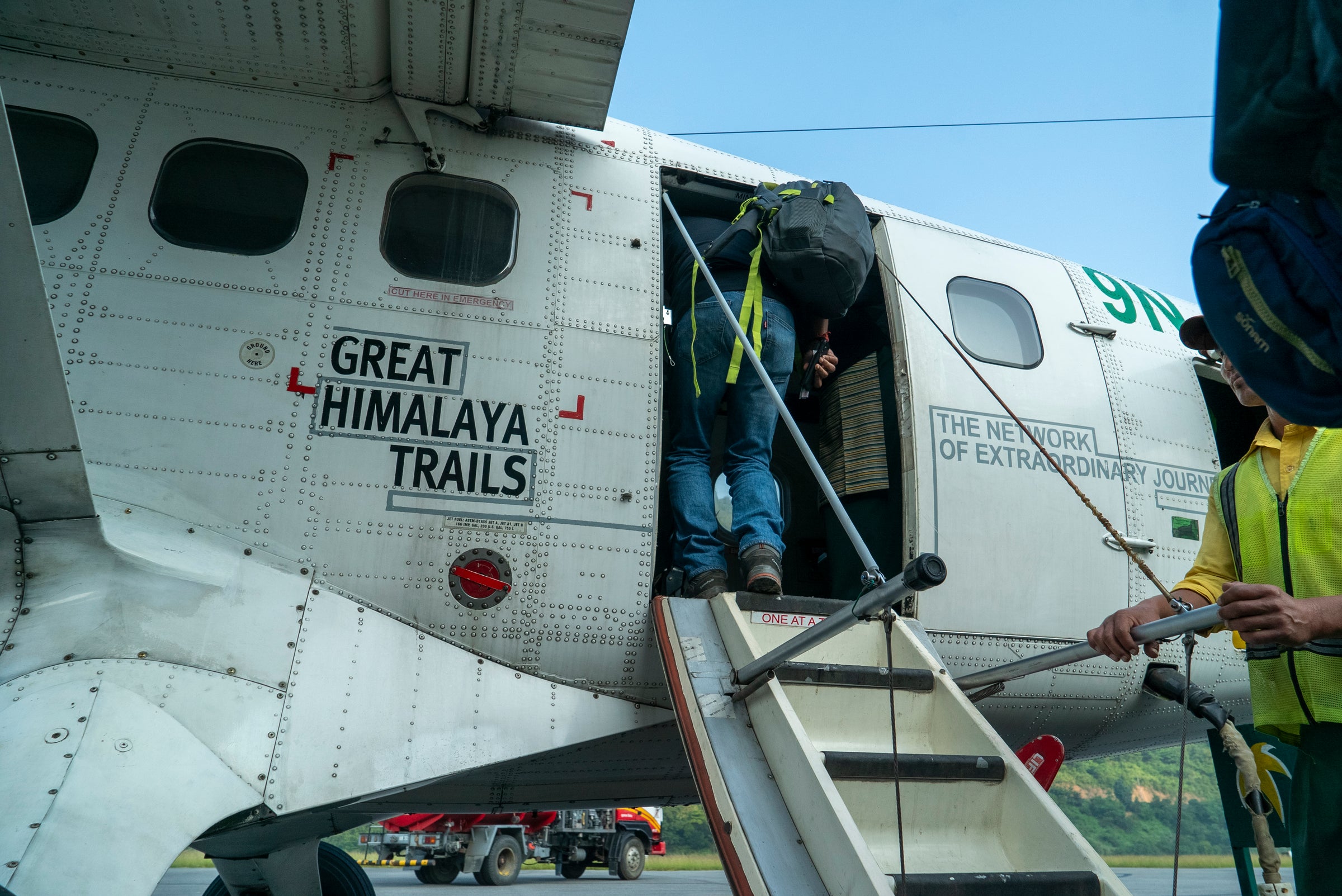 People boarding a small airplane with 'Great Himalaya Trails' branding.