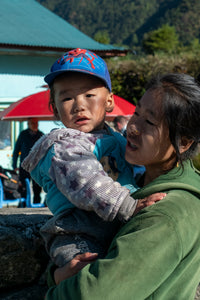 Woman holding a child outdoors with mountains in the background
