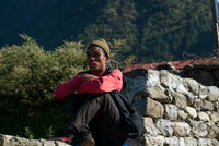 Person sitting on a stone wall with a mountainous background