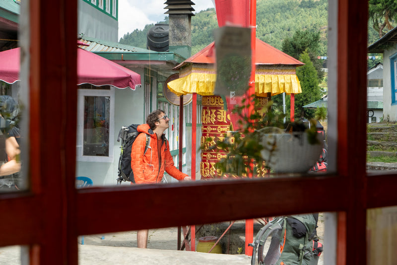 Person with a backpack reflected in a window with a scenic background