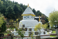 White stupa with gold accents in a garden setting