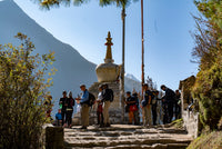Group of people standing around a stupa with mountains in the background