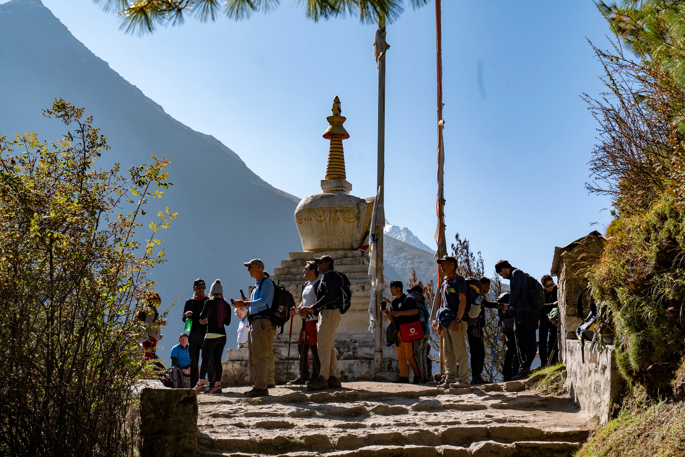 Group of people standing around a stupa with mountains in the background