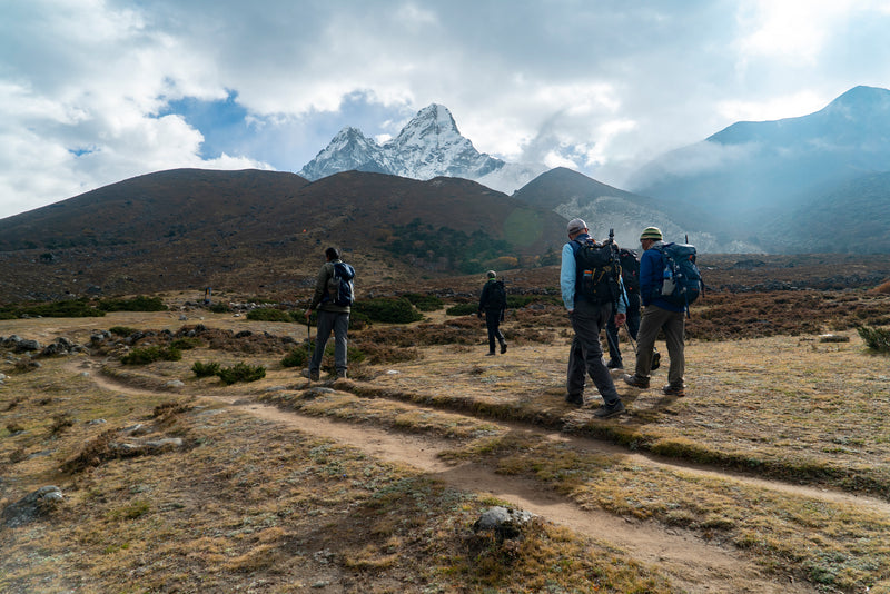 Hikers with backpacks walking on a trail with mountains in the background