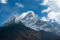 Snow-capped mountain peaks under a blue sky with scattered clouds