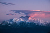 Snow-capped mountains with a pinkish hue on a cloud-covered sky