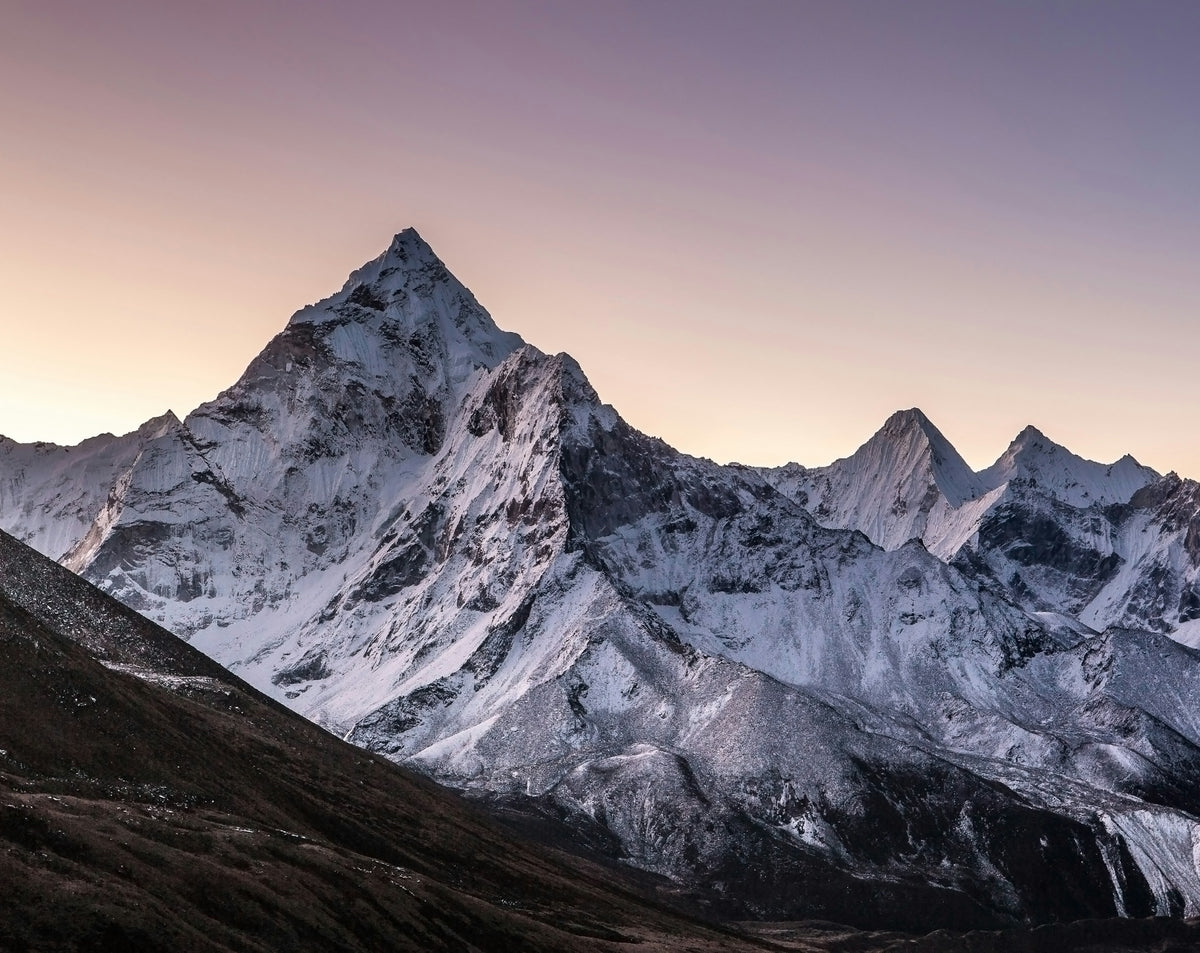 Snow-capped mountain peaks under a pinkish-purple sky