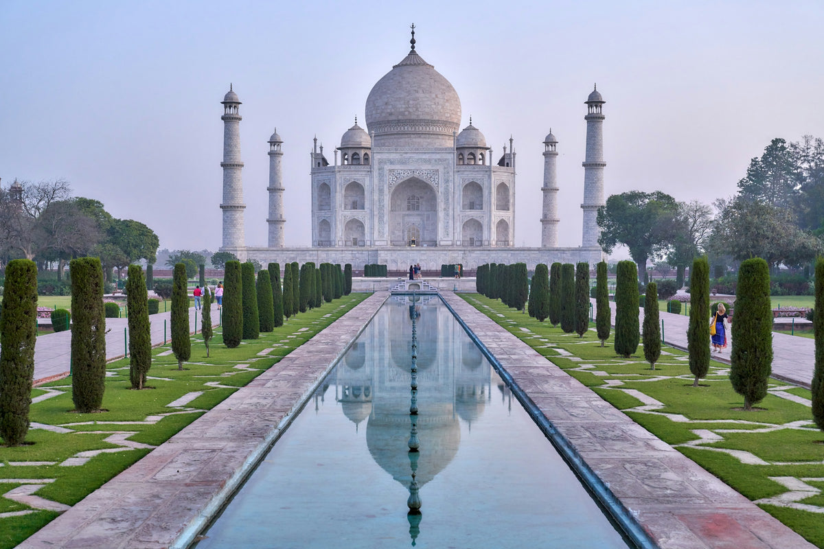 The Taj Mahal with a reflection in a pool, surrounded by well-manicured gardens.