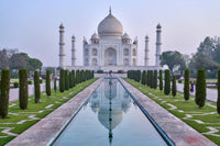 The Taj Mahal with a reflection in a pool, surrounded by well-manicured gardens.