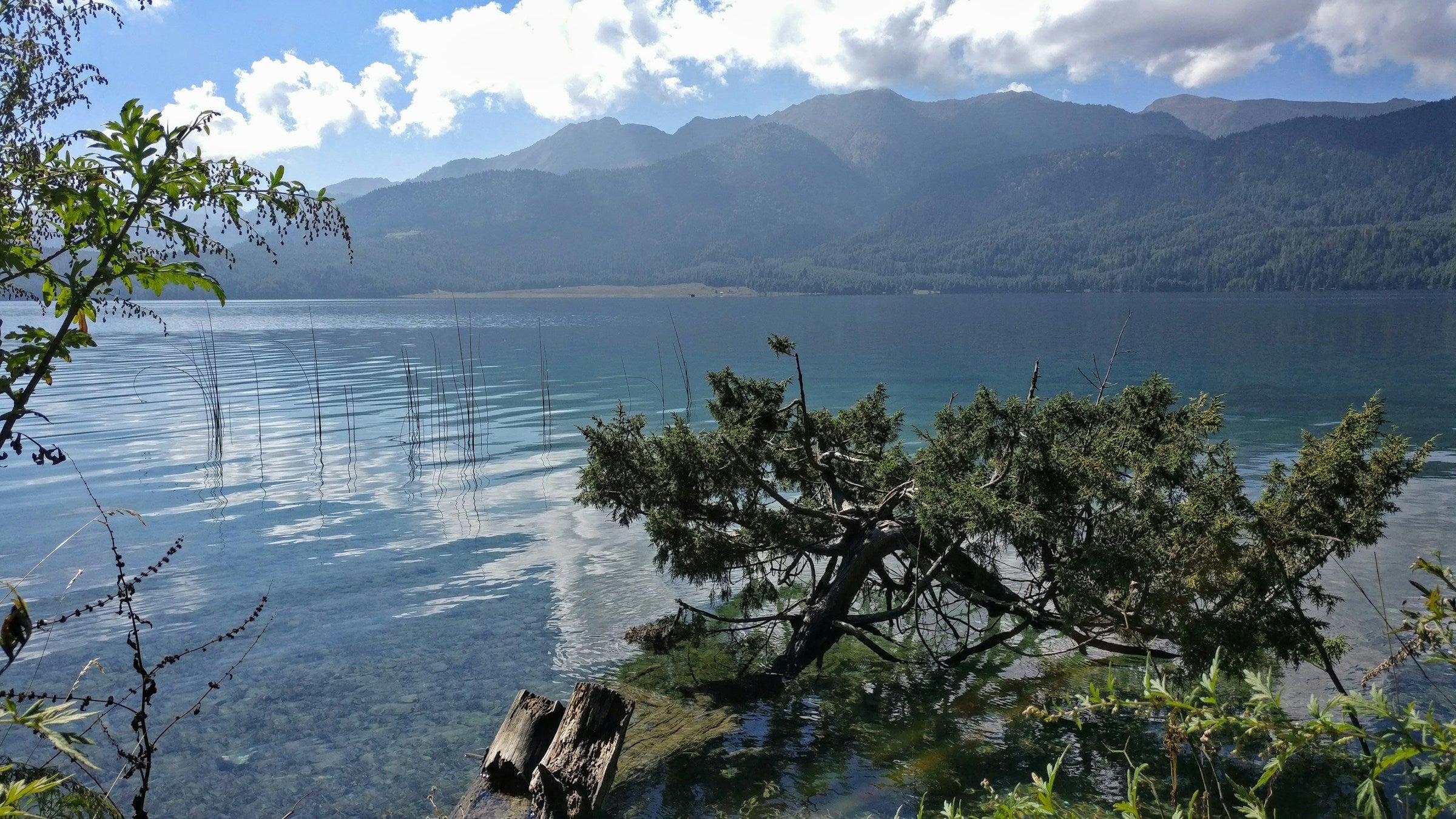 Lake with mountains in the background under a blue sky with clouds