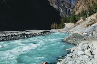 Turquoise river flowing through a mountainous landscape with rocky banks.