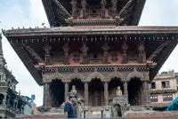 Traditional Nepalese temple with intricate architecture and a person standing in front.