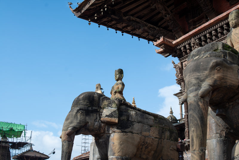 Statues of elephants and a person on an elephant with architectural elements in the background.