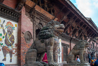 Stone lion statues in front of a traditional building with intricate carvings.