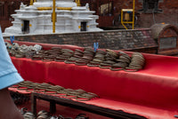 Red bench with metal chains and a white stone structure in the background