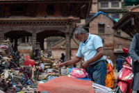 Man shopping at an outdoor market with traditional architecture in the background