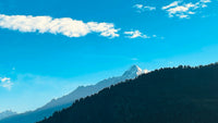 Mountain range with a clear blue sky and scattered clouds